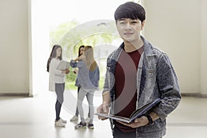 education, school and people concept - Cheerful university students with a book on group of students in background at each other