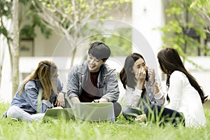 education, school and people concept - Cheerful university students with laptop on group of students in background at each other