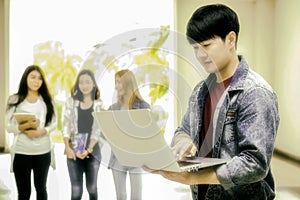 education, school and people concept - Cheerful university students with laptop on group of students in background at each other