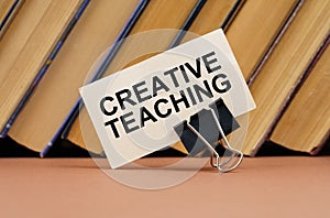 On the table against the background of books is a business card with the inscription - Creative Teaching photo