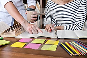 Education, teaching, learning concept. Two high school students or classmates group sitting in library with helps friend doing