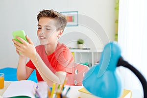 Student boy with smartphone distracting from study photo