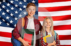 Education In USA. Happy kids with backpacks posing over American flag background