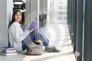 Educational concept. A modern girl student sits on the floor and reading joyfully a book. Modern generation. Reading.