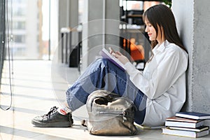 Educational concept. A modern girl student sits on the floor and reading joyfully a book. Modern generation. Reading.