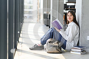 Educational concept. A modern girl student sits on the floor and reading joyfully a book. Modern generation. Reading.