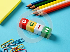 Educational exam or question games concept. The word quiz on colorful cubes with stationery objects on blue background