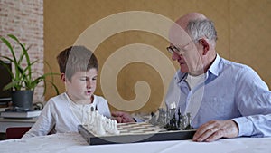 Educational games, caring old man in glasses for vision plays board games with his smart grandson