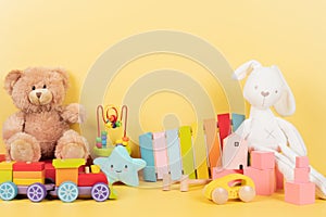 Educational kids toys collection. Teddy bear, train, xylophone, wooden educational baby toys on yellow background. Front