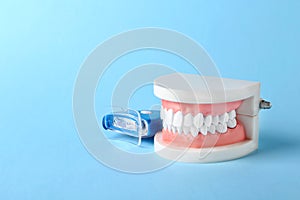 Educational model of oral cavity with teeth and whitening device on color background.