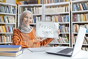 Educator in hijab teaches English grammar in library setting photo