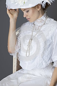 An Edwardian woman wearing a white lace blouse and skirt and a large hat