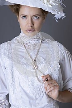 An Edwardian woman wearing a white lace blouse and skirt and a large hat