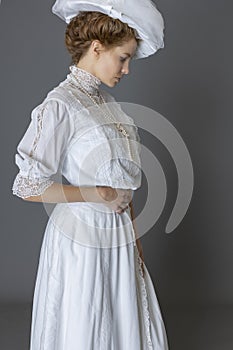 An Edwardian woman wearing a white lace blouse and skirt and a large hat