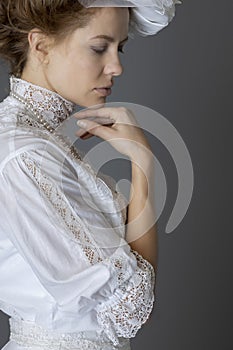 An Edwardian woman wearing a white lace blouse and skirt and a pearl necklace