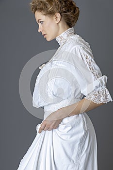 An Edwardian woman wearing a white lace blouse and skirt and a pearl necklace