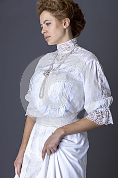 An Edwardian woman wearing a white lace blouse and skirt and a pearl necklace