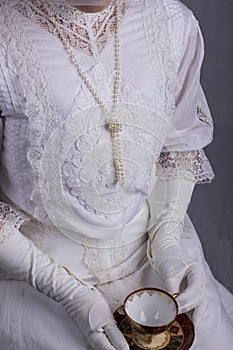 Edwardian woman in white blouse and skirt holding a tea cup