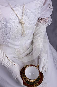 Edwardian woman in white blouse and skirt holding a tea cup