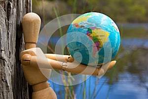 Eearth globe in hands of wooden doll wildlife and environment protection concept