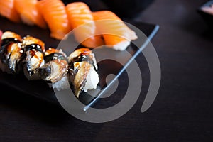 Eel and salmon sushi sashimi on black dish with empty table