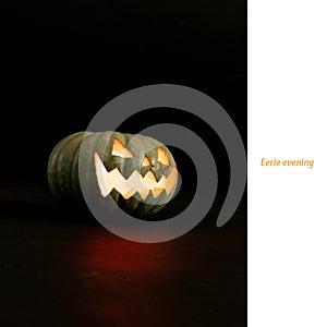 Eerie evening text on white and carved jack o lantern halloween pumpkin on black background