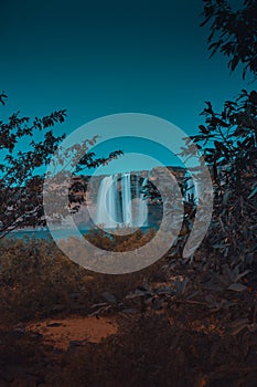 Eerie scenery of the Chitrakote Falls on the Indravati River behind trees in India