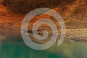 Eerie scenery of an old wooden shallop on the shore of a lake