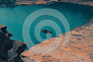 Eerie scenery of people on an old wooden shallop on the blue waters of a lake