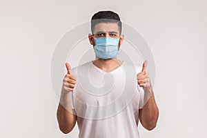 Effective protection against contagious disease. Man showing thumbs up and wearing hygienic mask