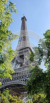 Effel tower in Paris against a bright blue sky and green trees photo