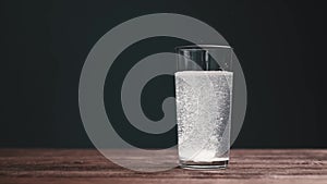 Effervescent aspirin pill falling into a glass of water.