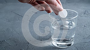 An effervescent aspirin tablet is thrown into a glass of water. Background with space for text