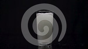 Effervescent tablet falling in a glass of water in slow motion