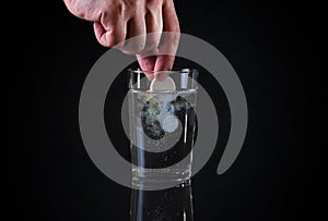 The effervescent tablet in hand over a glass of water