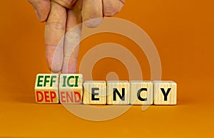 Efficiency or dependency symbol. Businessman turns cubes, changes the word dependency to efficiency. Beautiful orange table,