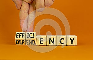 Efficiency or dependency symbol. Businessman turns cubes, changes the word dependency to efficiency. Beautiful orange table,