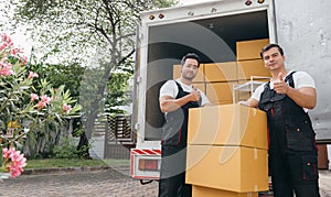 Efficient workers in uniform unload boxes from the moving truck ensuring a