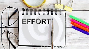 EFFORT written in a notebook on white background with office tools