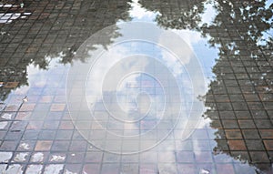 Eflection of sky sun & clouds in cement brick floor background