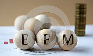 EFM - abbreviation on wooden balls on a background of coins and graphics