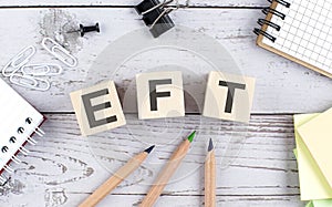 EFT text on wooden block with office tools on the wooden background