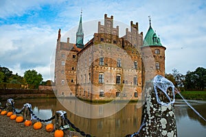 Egeskov, Denmark, Halloween: Orange pumpkins decorate the bridge across the lake. Beautiful Egeskov castle in autumn