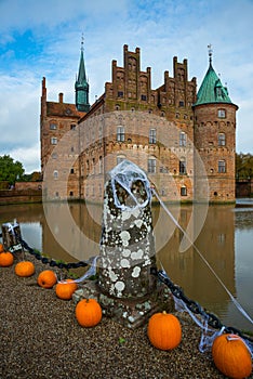 Egeskov, Denmark, Halloween: Orange pumpkins decorate the bridge across the lake. Beautiful Egeskov castle in autumn