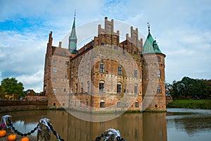 Egeskov, Denmark, Halloween: Orange pumpkins decorate the bridge across the lake. Beautiful Egeskov castle in autumn