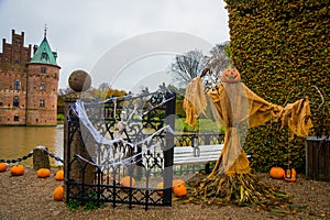 Egeskov Slot, Denmark, Halloween: Scarecrows and pumpkins decorate the entrance to the bridge to the Egeskov Castle in autumn