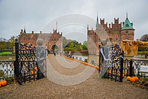 Egeskov Slot , Denmark, Halloween: Scarecrows and pumpkins decorate the entrance to the bridge to the Egeskov Castle in autumn