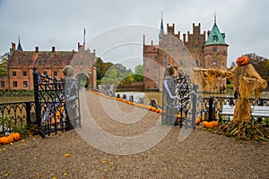 Egeskov Slot , Denmark, Halloween: Scarecrows and pumpkins decorate the entrance to the bridge to the Egeskov Castle in autumn