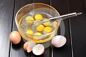 Egg beater on a glass bowl with eggs