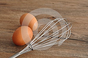 An egg beater, with two eggs